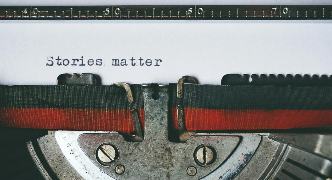 Close-up of a vintage typewriter typing the words 'Stories matter' on a sheet of paper.